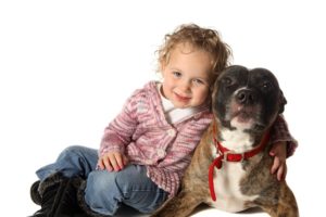 cachorro pitbull ao lado de uma criança
