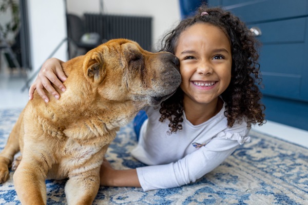 Menina feliz ao lado de cachorro. 