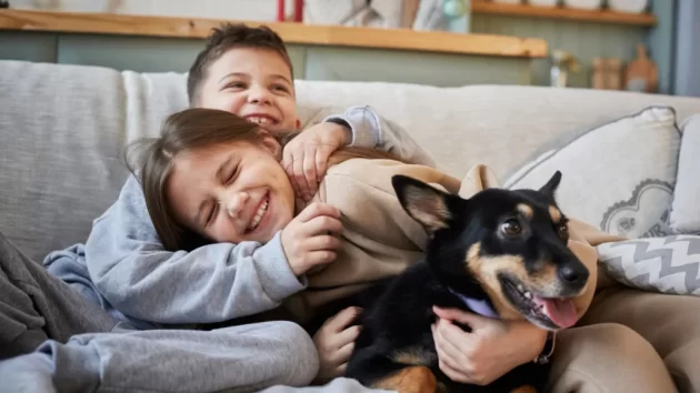 Petlove - crianças abraçadas com um cachorro, sorrindo e felizes. Dia internacional do cachorro, cuidados com pets